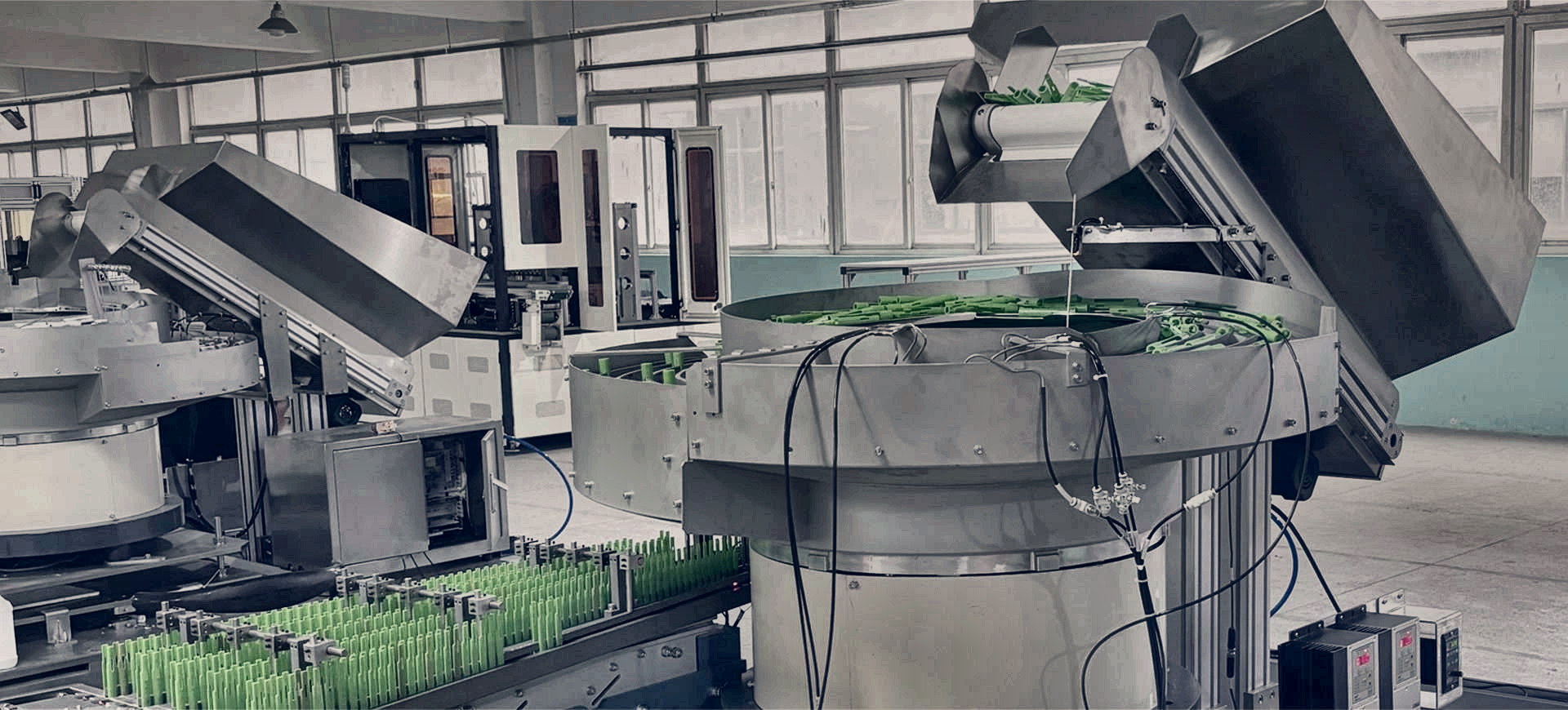 Installed component feeding production line with vibratory bowl feeders, bulk elevators and conveyor presentation